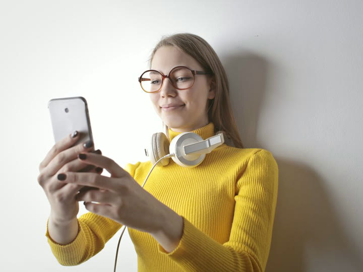 Une créatrice, téléphone en main, sourit — ton premier vidéo clip gratuit